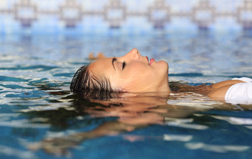 Profile of a beauty relaxed woman face floating in water of a pool enjoying vacations